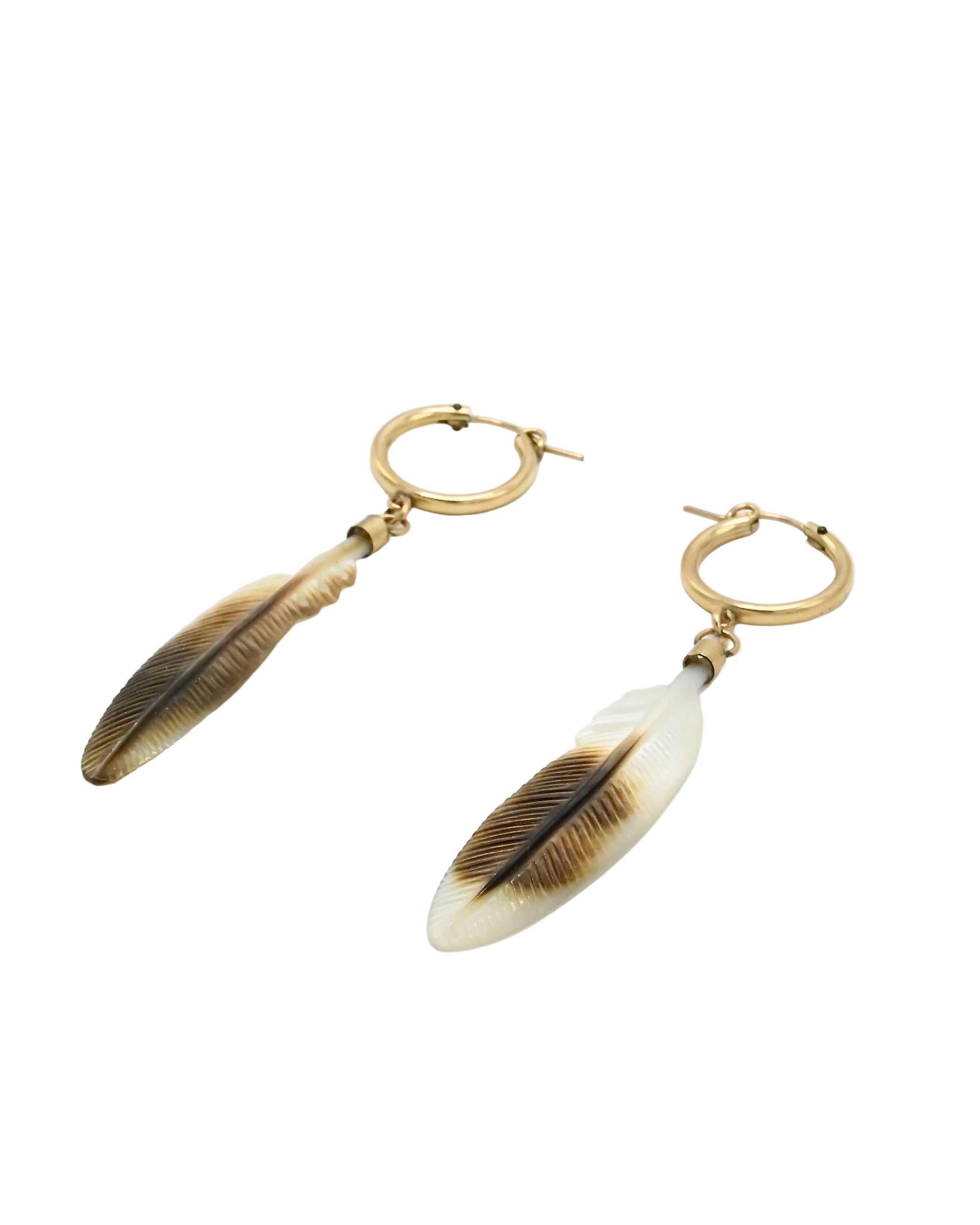 A pair of gold hoop drop earrings with feather charms. The feather charms are made of a material that looks like bone or resin, featuring a cream-white base with brown and black feather details.