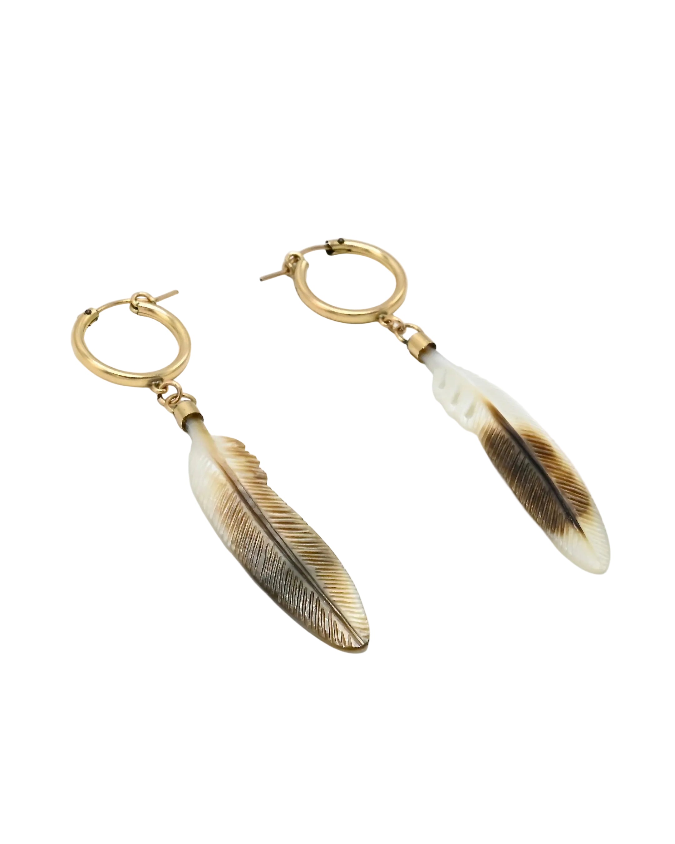 A pair of gold hoop earrings with dangling feather charms. The feathers are cream and brown with detailed feather line patterns, shown on a plain light gray background.