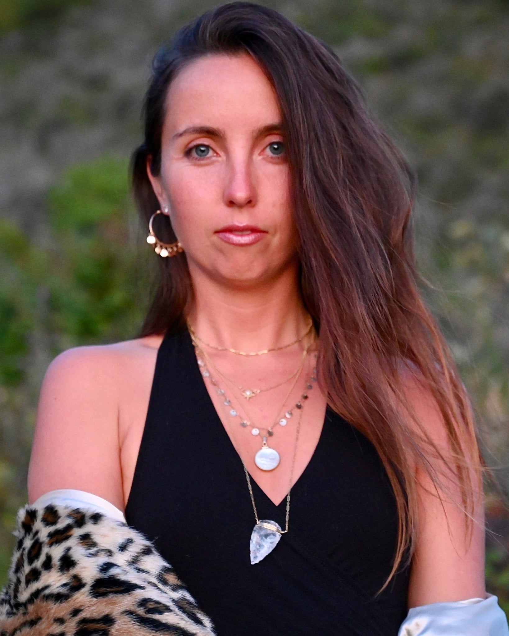 Woman wearing a black top and leopard print sleeve with a blurred natural background
